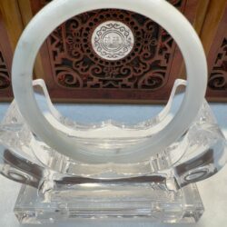 Translucent white jade bangle with wood backdrop