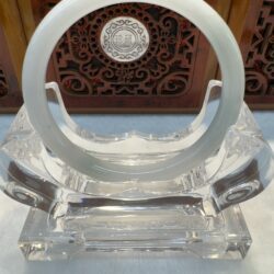 Translucent jade ring on decorative stand.
