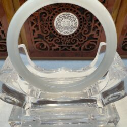 White jade circular bracelet on glass stand
