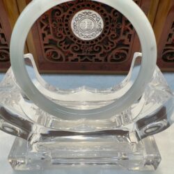 Crystal display stand with ornate background design.