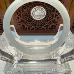 Translucent circular jade bangle on acrylic stand