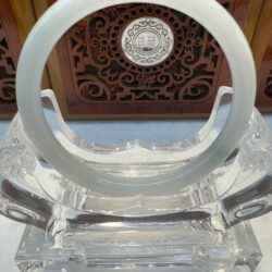 Circular pale jade bangle with carved backdrop