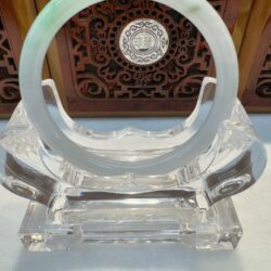 Circular jade bangle on ornate wooden carving