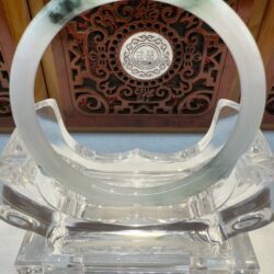 Circular jade ornament on ornate wooden background.