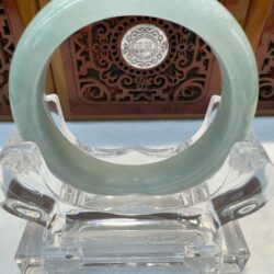 Translucent green jade bangle centered on stand