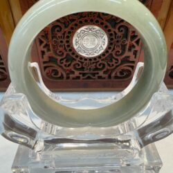 Olive-toned jade circle against ornate wooden medallion