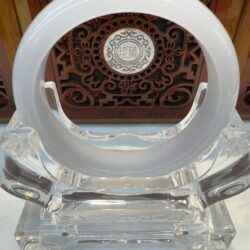 White jade bangle on a decorative stand.