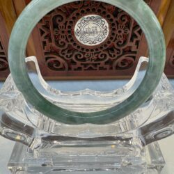 Darker green jade bangle on clear stand