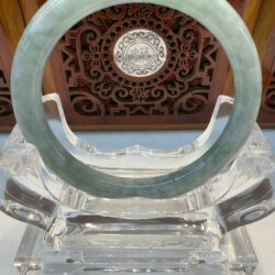 Polished jade hoop against carved wood backdrop