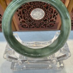 Circular pale jade pendant with wooden backdrop