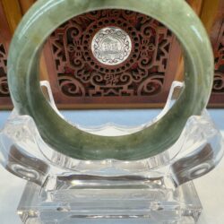 Circular pale jade bracelet with wooden backdrop