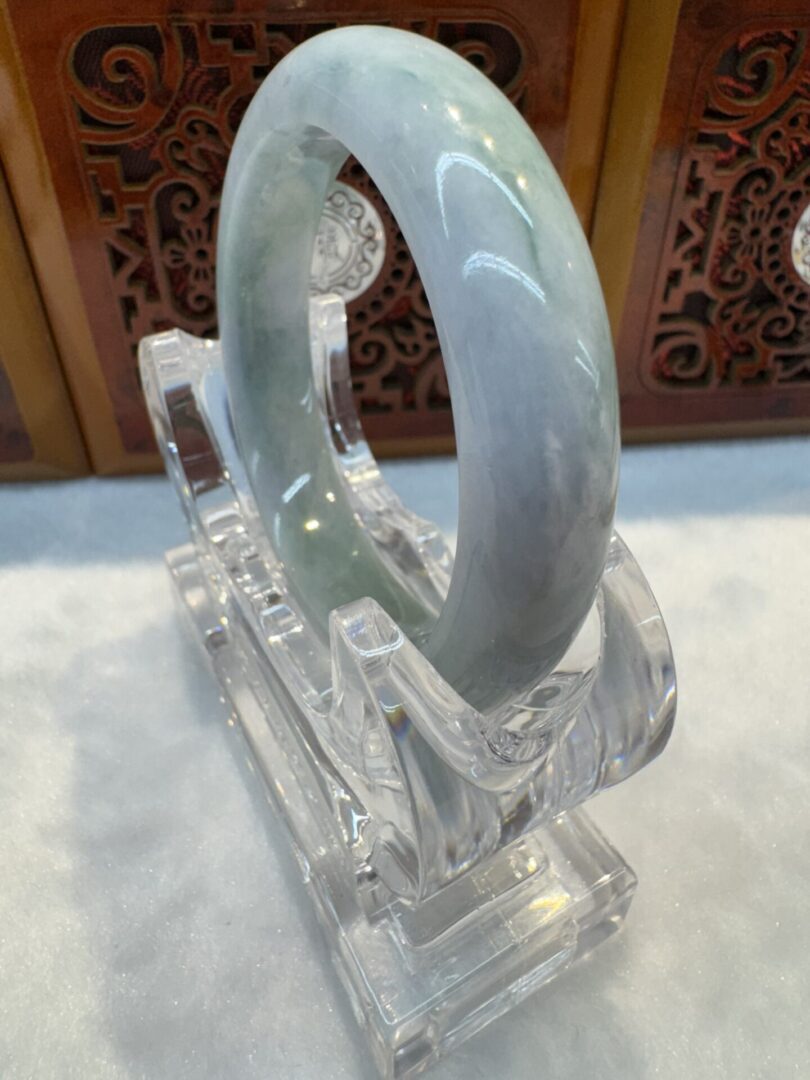 Angled grey-green jade bangle on acrylic stand