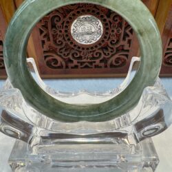 Green jade circle on ornate wooden stand.