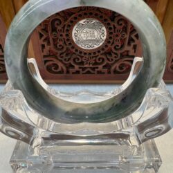 Jade circle on decorative wooden stand.