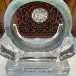 Pale green jade bangle with ornate backdrop