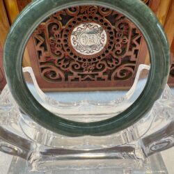 Dark mottled jade bangle with carved backdrop