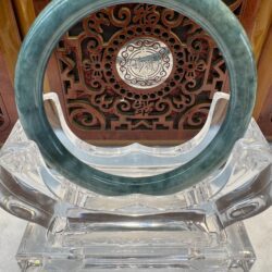 Green jade circle on ornate wooden display.
