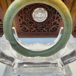 Green and yellow jade bangle on stand.