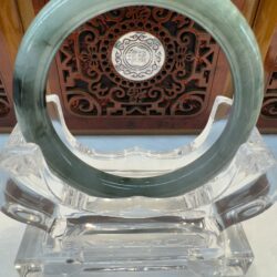 Circular light-green jade bangle on acrylic stand