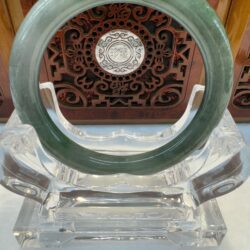 Dark green jade bangle on acrylic stand
