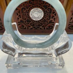 Green jade hoop displayed before carved panel