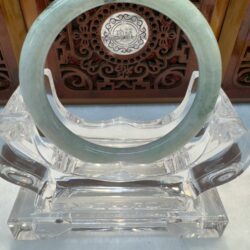 Jade ring on ornate clear stand display.