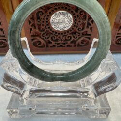Polished green jade bi displayed on acrylic