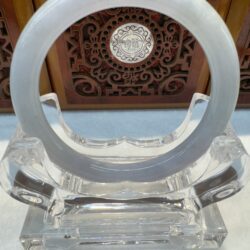 Circular jade sculpture with intricate wooden background.
