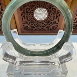 Circular jade bangle with carved wooden backdrop