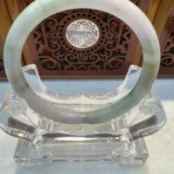 Green-tinged jade bracelet displayed on stand