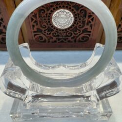 Circular pale jade bangle centered on stand