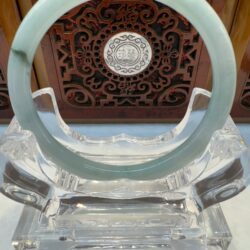 Jade bangle on ornate stand display.