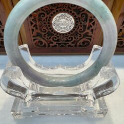 Soft lavender-green jade bracelet angled on stand