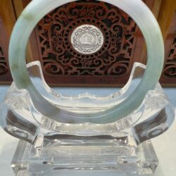 Jade bangle on an ornate wooden stand.