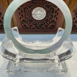 Green hued jade bangle framed by ornate panel