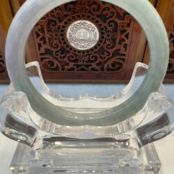 Jade ring displayed on ornate stand.