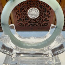 Pale green jade bracelet framed by wooden carving