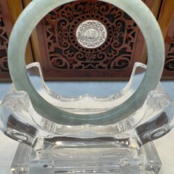 Translucent pale green jade bracelet on clear stand