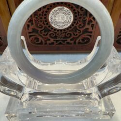 Smooth jade cuff showcased before carved screen