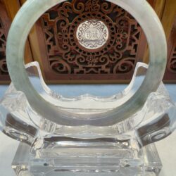 Jade bangle on display with intricate background.