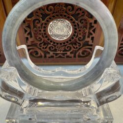 Round jade bracelet against carved panel