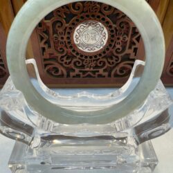 Mint green jade bangle displayed on acrylic base