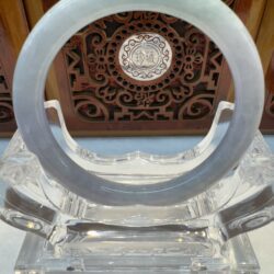 Jade ring on ornate wooden background stand.