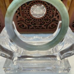 Green-toned jade bangle with wood backdrop