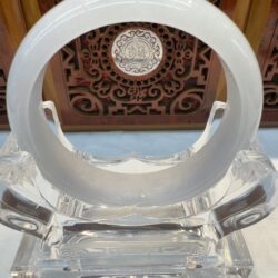 Round white jade cuff resting on crystal stand