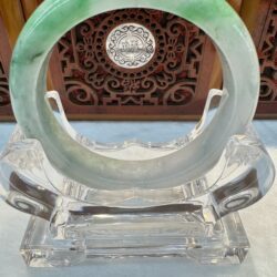 Translucent light green jade bangle on clear stand