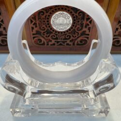 Ornate circular object on clear display stand.