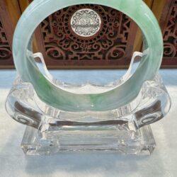 Translucent green jade bi on crystal stand