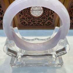 Purple jade bracelet on clear stand.