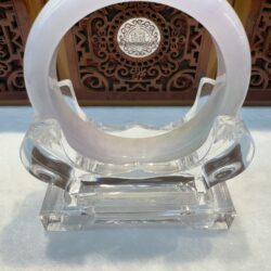 Polished jade hoop perched on clear pedestal